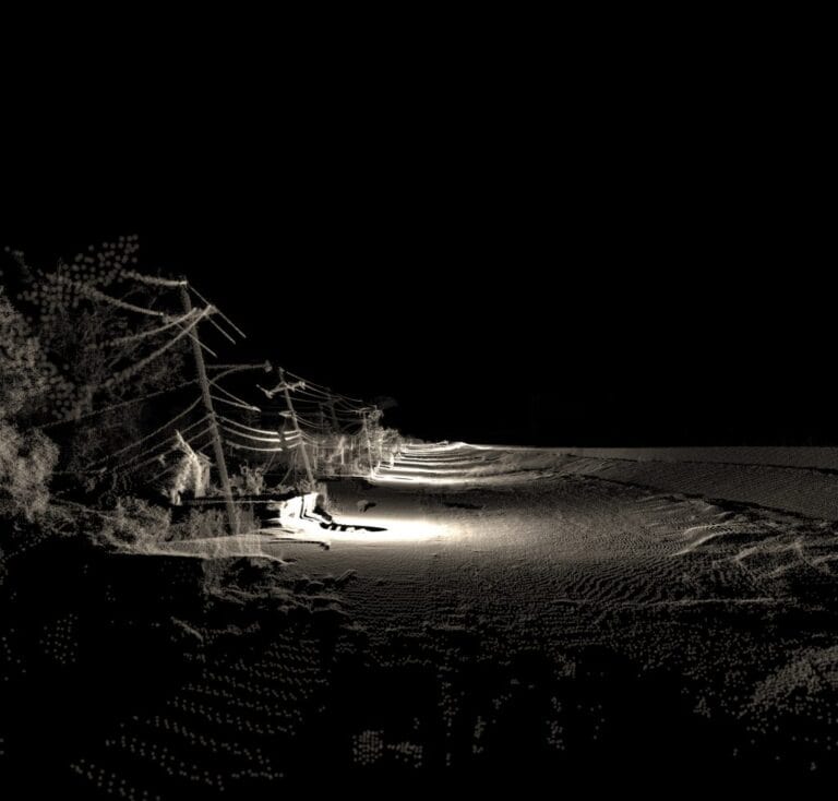 A black and white image of a desolate, dark landscape. Alongside a dirt road that stretches into the distance, rows of leaning electric poles line its left side. Shadows and sparse light create an eerie, almost apocalyptic atmosphere—a scene where artists trade ideas in whispered tones.