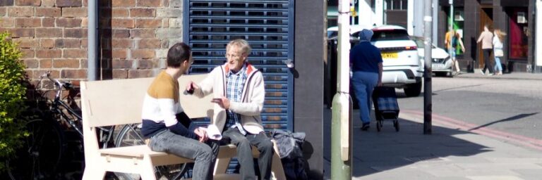 two people sitting on a bench in conversation