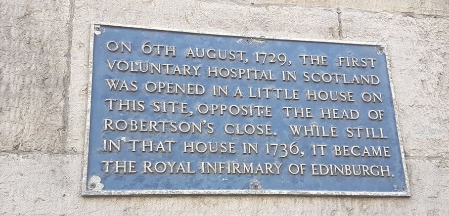 Plaque reads: 'On 6th August, 1729, the first voluntary hospital in Scotland was opened in a little house on this site, opposite the head of Robertson's Close. While still in that house in 1736, it became the Royal Infirmary of Edinburgh.