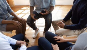 People sitting in a circle, only their lower bodies are visible in this image.