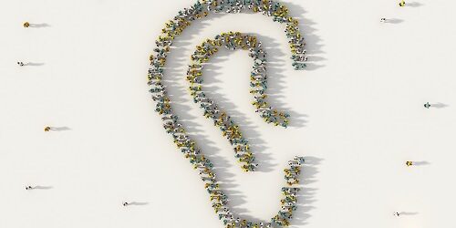 Large group of people from above forming an ear symbol on white background.