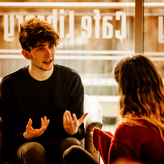 Male student talking with female student, orange tint