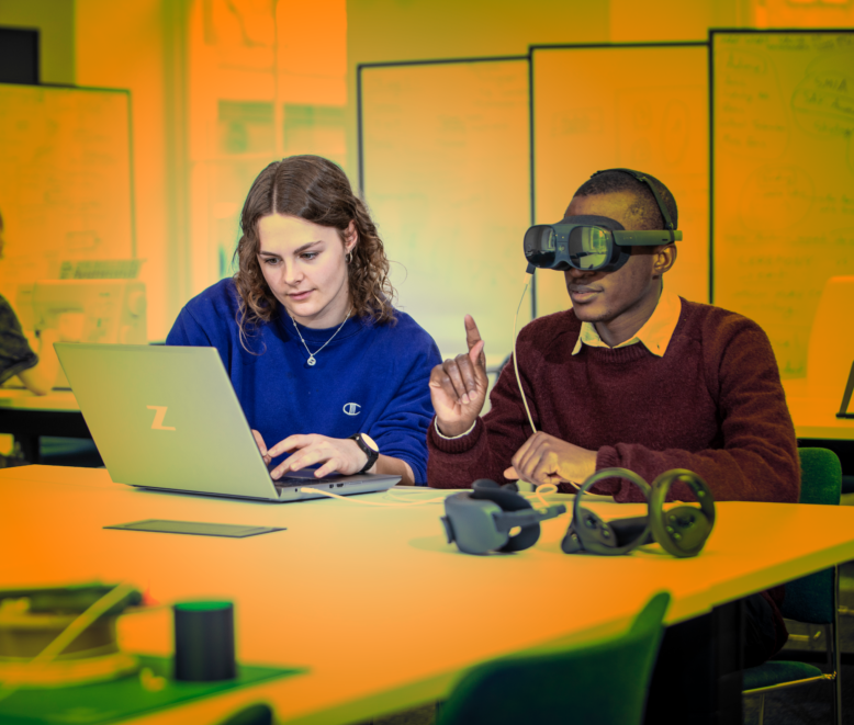 2 students in class, one is wearing a virtual reality headset