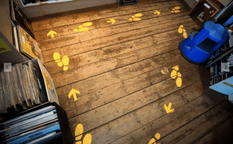 Yellow footsteps and arrows printed on wooden floor