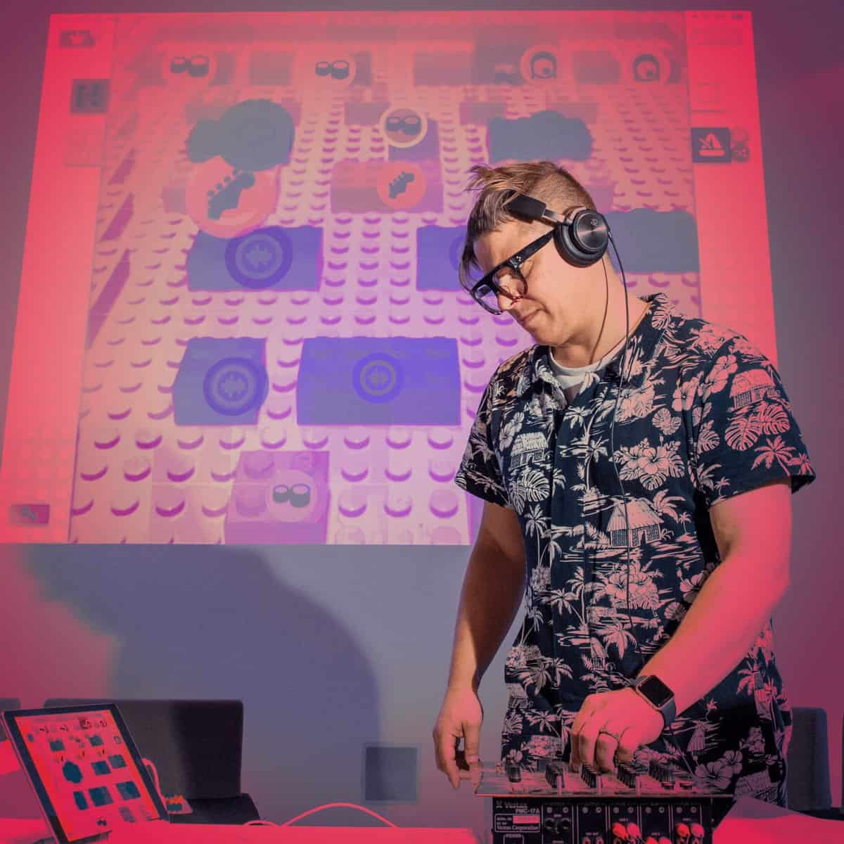 A DJ standing over his decks, red tint over image.