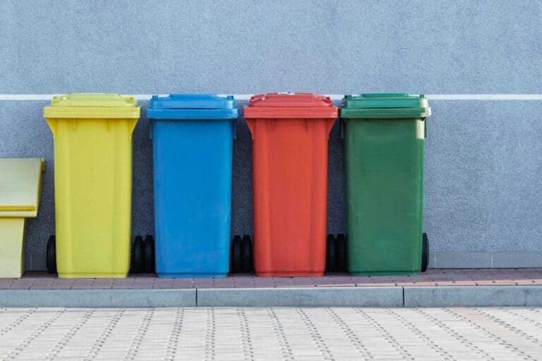 different coloured recycling bins lined up against wall