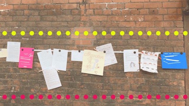 A brick wall is decorated with a horizontal string of various papers, flyers, and posters attached with clothespins. The top and bottom of the image are bordered with rows of yellow and pink dots, respectively.