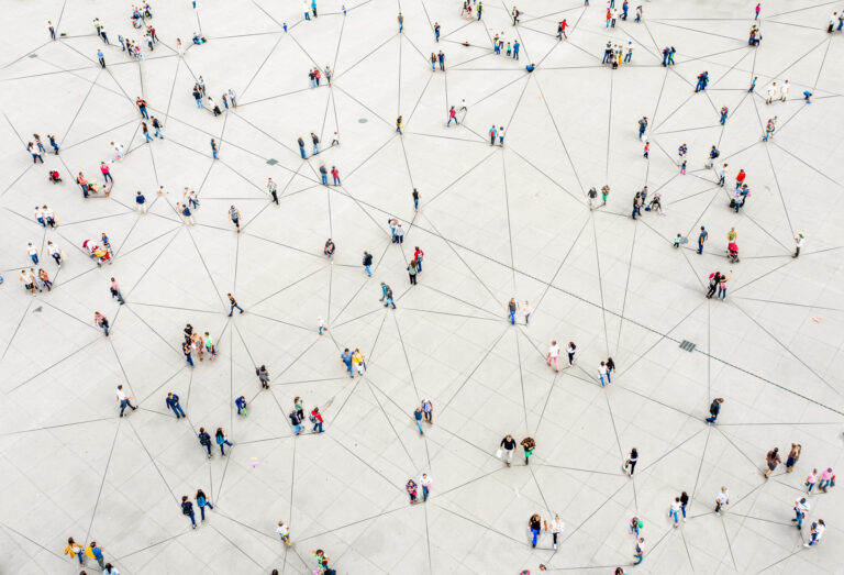 Aerial view of a large paved area with groups of people connected by black straight lines, forming a complex network pattern. The scene gives an impression of social connections among individuals. The people are spaced out and various activities are seen from above.