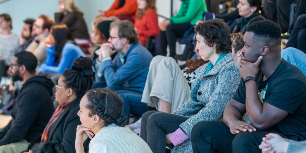 A photograph of an audience watching an event which is out of shot.