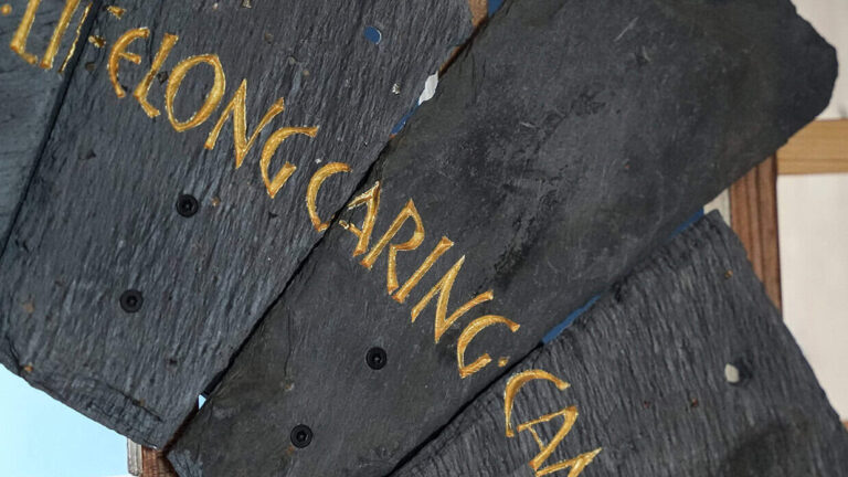 Slate from the Spirit Case sculpture displaying the words 'caring'