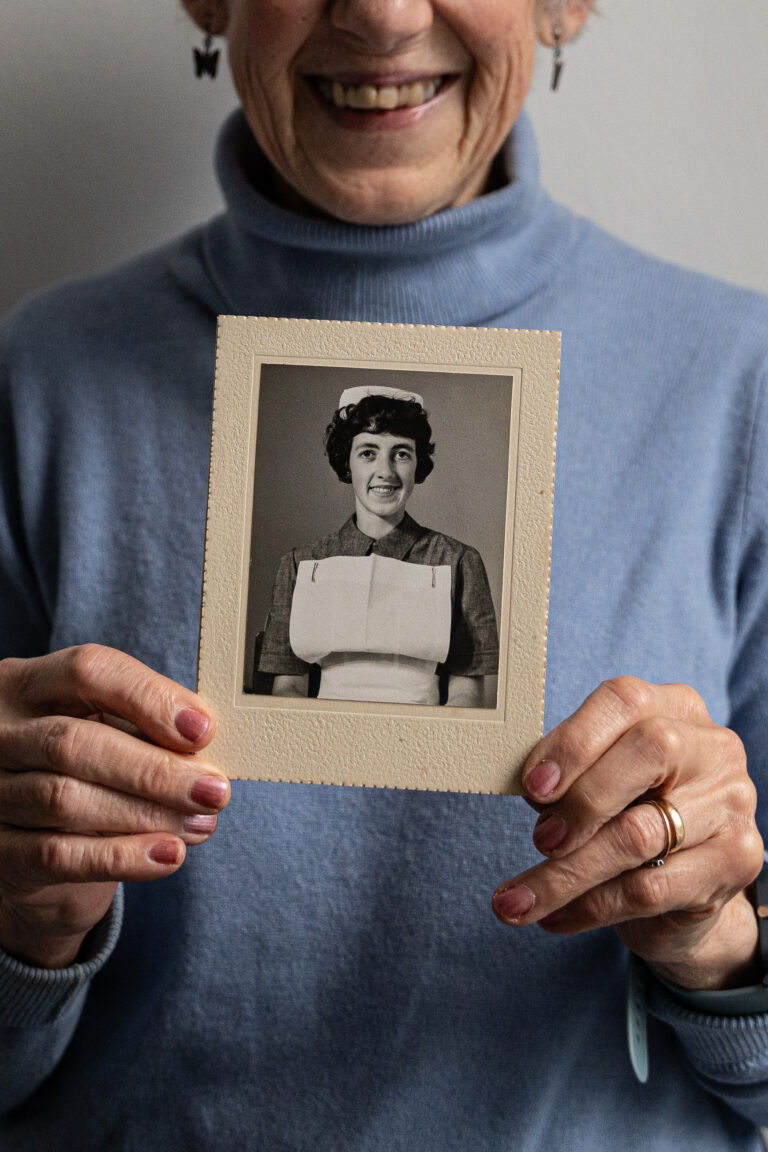 Joan Bell holding an old photograph of herself as a student nurse