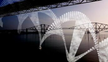 A suspension bridge spans across a calm river under a clear sky, with large white DNA helix structures superimposed over the scene. Another bridge is visible in the background, enhancing the architectural perspective.