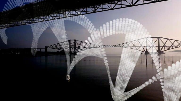 A suspension bridge spans across a calm river under a clear sky, with large white DNA helix structures superimposed over the scene. Another bridge is visible in the background, enhancing the architectural perspective.