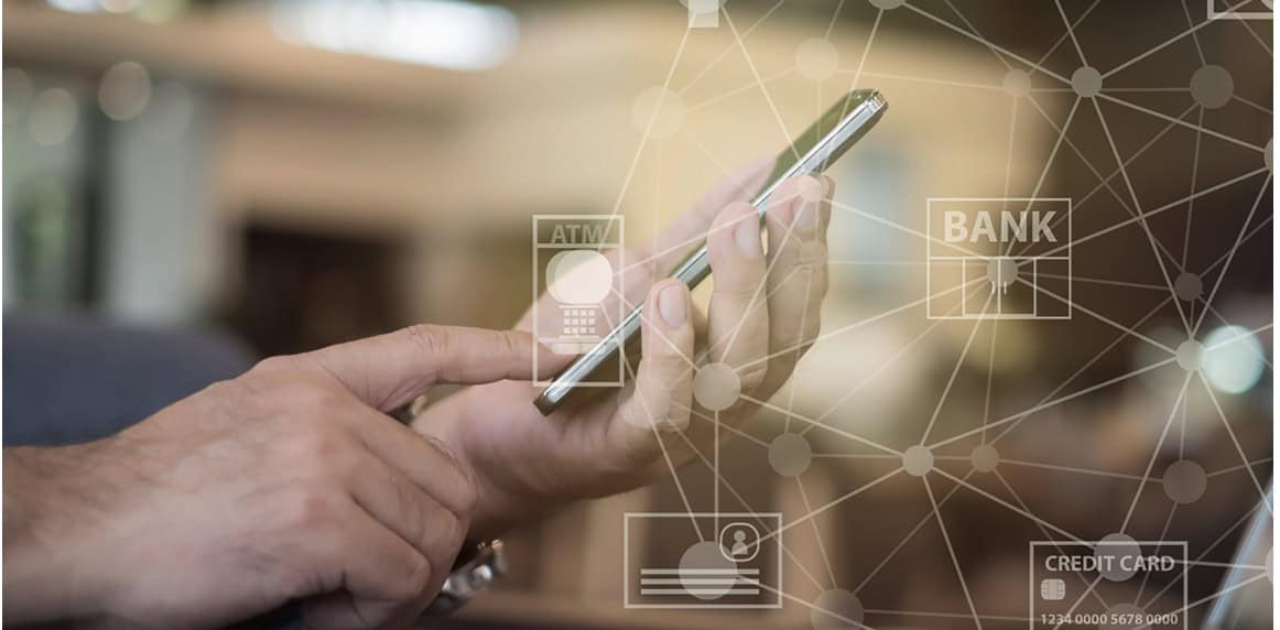 Person using a smartphone with virtual icons related to banking, such as ATM, bank, and credit card, overlaid on the image. The background is blurred, highlighting the focus on digital finance technology.