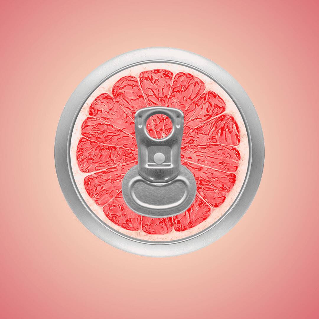 A close-up of a beverage can's pull tab, with the top resembling a sliced red grapefruit. The grapefruit appears juicy and vibrant. The background is a gradient of pink and red, enhancing the fruit's color.