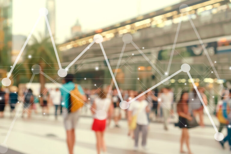 A blurred crowd of people outdoors with an overlaid graphic of connected lines and data points, symbolizing data analysis or statistics in a public setting.