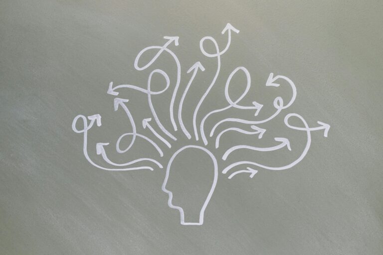 White outline of a human head on a grey background, with multiple arrows emerging from the head and curving in various directions, symbolizing thoughts, ideas, or decision-making.